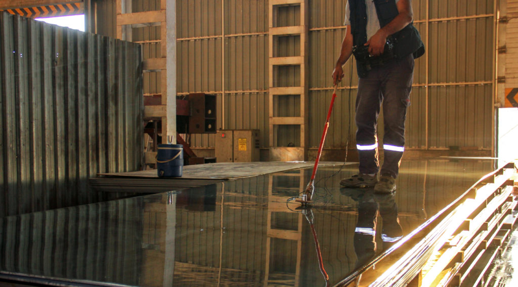 The inspector is checking to steel plates with an ultrasonic test device for lamination.